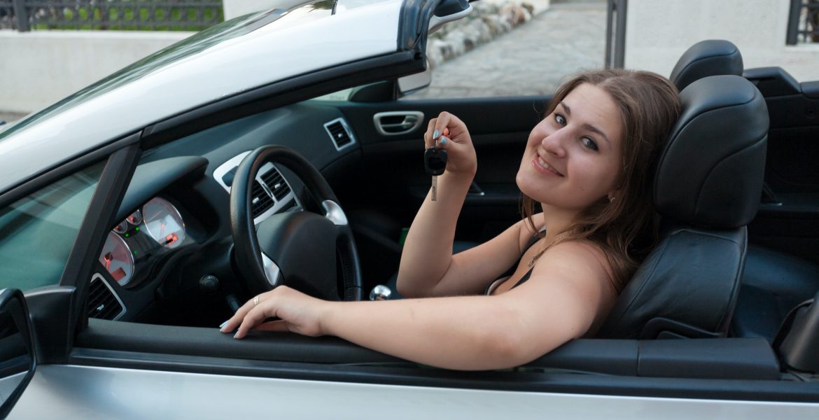 smiling woman sitting in convertible car and holding car keys